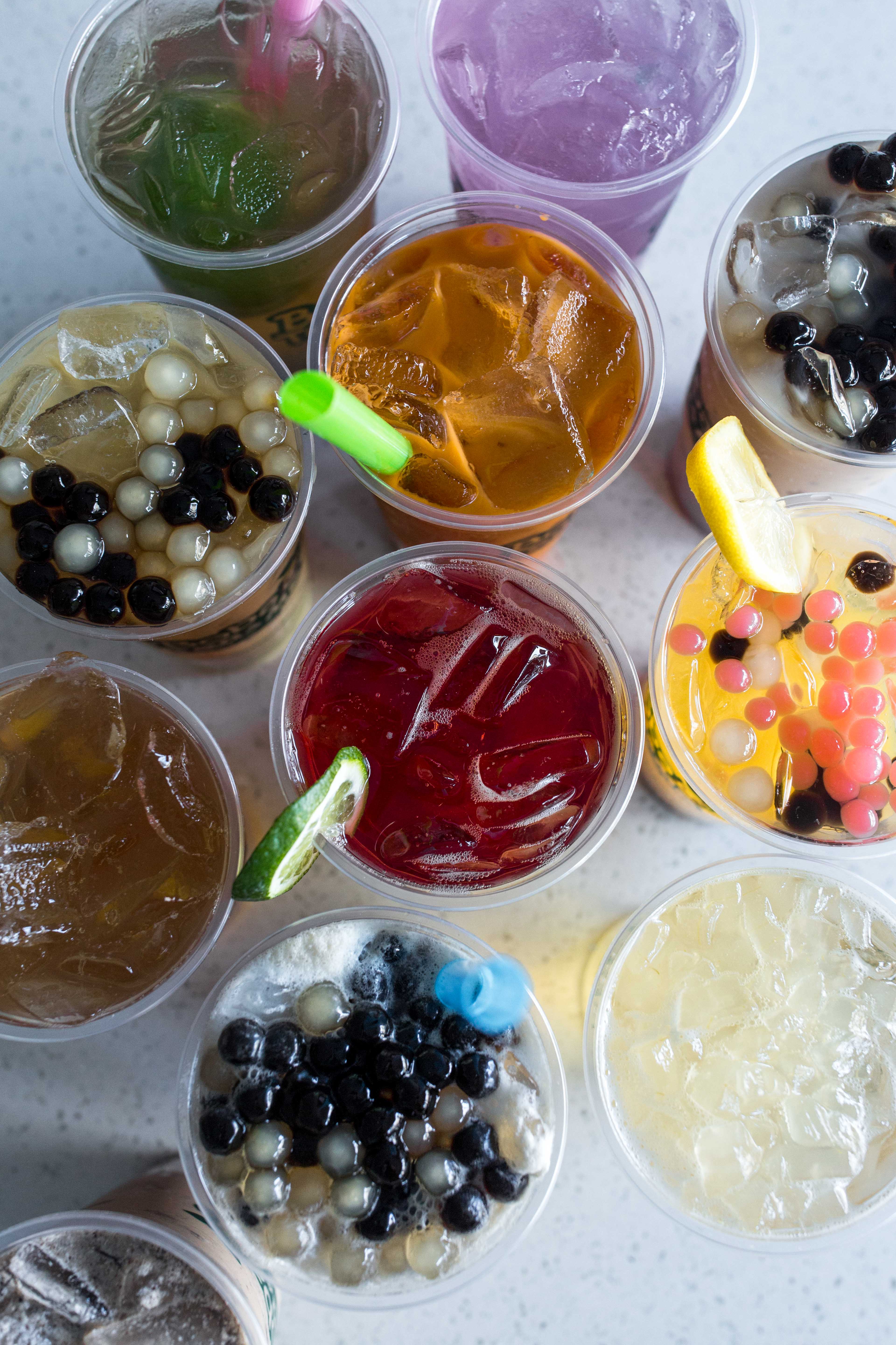 A top-down view of assorted Boba Tea & Me drinks with boba and fruit toppings.